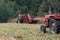 A tractor pulls a corn harvester and picks dry ripe corn in the field