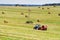 Tractor pulls Round Baler in the background of a field