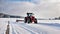 The tractor pulls a snowy car in the snow in winter landscape in