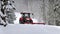 The tractor pulls a snowy car in the snow in winter landscape in