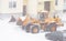 Tractor removing snow near a house during a blizzard