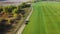 A tractor rides on a road along a green field. Farm work in early autumn. Aerial footage