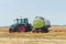 Tractor and round baler discharges. Straw Bales.