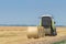 Tractor and round baler discharges. Straw Bales.