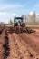 The tractor's engine hums as it pulls the seed drill, ensuring an even distribution of seeds across the field