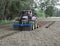 Tractor with seed drill and Front Packer which compacts the soil punctiformly into the depth