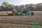 Tractor with seed drill and Front Packer which compacts the soil punctiformly into the depth