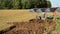 Tractor slowly ploughing farm field soil