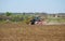 Tractor sows wheat and rye on a plowed field on a spring sunny day