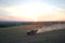 Tractor spraying fertilizers with insecticide herbicide chemicals on agricultural field at sunset