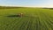 Tractor spraying pesticides on soybean field with sprayer at spring. Aerial Quadcopter Shooting