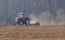 Tractor with a towing roller compactor levels the surface of the plowed field to prepare the sowing