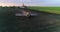 Tractor with trailed sprayer spraying chemicals on agricultural field. Aerial view