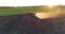 Tractor with trailed sprayer spraying chemicals on agricultural field. Aerial view