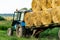 Tractor on trailer transports large round bales of hay. Transportation of hay to places for storage and drying of silage.