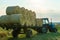 Tractor on trailer transports large round bales of hay. Transportation of hay to places for storage and drying of silage.