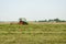 Tractor turning raking cut hay in field