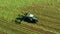 A tractor turns up the grass, aerial view.