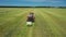 Tractor uses trailed bale machine to collect straw in field and make round large bales. Agricultural work, baling, baler