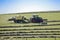 Tractor at work in field loading hay stacks