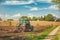 Tractor working on the farm, a modern agricultural transport, a farmer working in the field, fertile land, tractor on a sunset