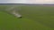 A tractor works in a green field. Aerial view