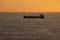 A trade cargo ship sailing alone at the sea in the Atlantic Ocean during sunset