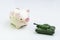 Trade war, economic impact of war or trading power concept, miniature tank toy pointing the gun at smiling pink piggy bank on