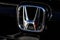 The trademark symbol of Honda in the frontside of a black car - photography