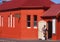 Tradesman wearing white overalls and carrying a paint can and paint brush entering a small community hall