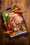 Tradition roasted lamb leg with carrot and fresh herbs in rustic bowl on wooden background