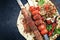 Traditional adana kebap skewer with tomato and salad on a flatbread