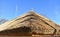 Traditional African thatched roof against a blue sky