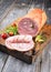 Traditional Allgauer veal roast roll sausage sliced and as piece with tomatoes and chili on an old rustic cutting board
