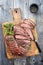 Traditional American barbecue dry aged flank steak sliced and on a rustic wooden board