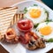 Traditional American continental breakfast. Fried eggs with bacon, mushrooms and toast. Plate of products with tomato