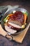 Traditional American meatloaf with ketchup from ground beef with carrots and onion in a copper saucepan