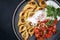 Traditional Armenian manti with mincemeat and paprika tomato salad on a modern design plate