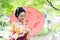 Traditional Asian Japanese beautiful Geisha woman bride wears kimono hold a red umbrella in a summer nature