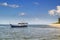 Traditional Asian wooden boat moves across the sea against a blue sky with clouds.