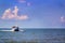 Traditional Asian wooden boat moves along the sea against the sunset sky with clouds.