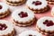 Traditional Austrian or German Linzer cookies with shortcrust pastry and jam filling on pink background