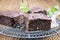 Traditional baked American brownies on a rustic cake plate on a wooden board