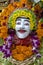 Traditional Balinese stone statuette of the deity decorated with flowers in the street temple. Island Bali, Indonesia . Close up