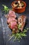 Traditional barbecue aged sliced venison sirloin with mushroom and herbs on a carbonized old board