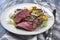 Traditional barbecue angus sirloin beef steak with artichoke hearts and pattypan squashes on a classic design plate