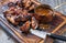 Traditional barbecue chicken wings with hot chili sauce on a burnt cutting board