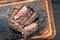 Traditional barbecue dry aged wagyu beef cutlet on a burnt wooden cutting board