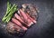 Traditional barbecue dry aged wagyu flank steak sliced with green asparagus on an old rusty board