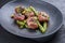 Traditional barbecue Iberian pork filet medaillons with green asparagus tips offered as close-up on a modern design cast iron blac